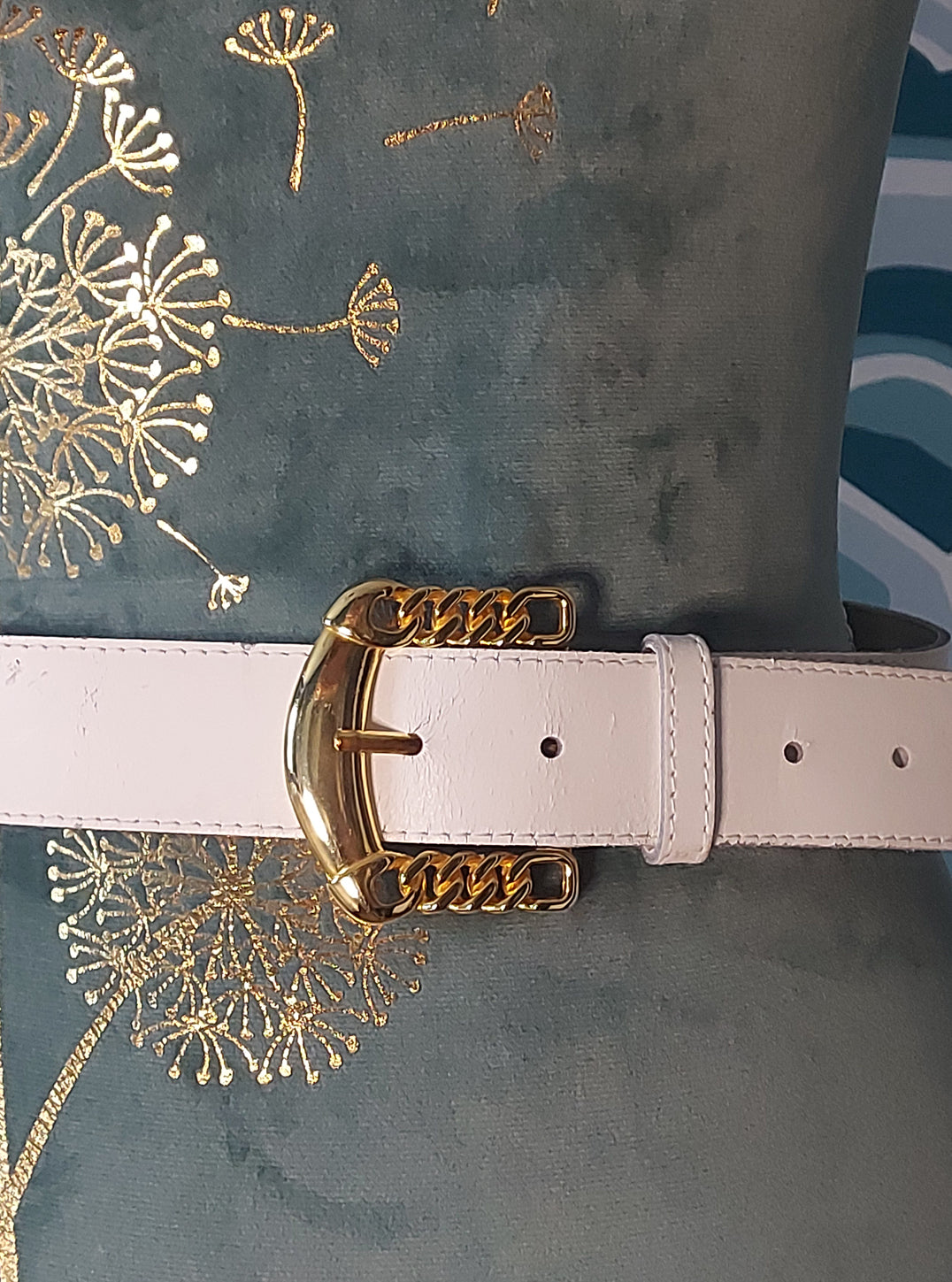 Close up of gold buckle on white belt
